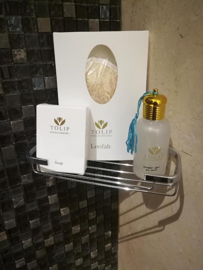 톨립 리조트 엘 갈라라 마제스틱 아인 수크나 외부 사진 The photo shows a small metal shelf containing three items related to personal care. 

1. **Soap**: A white box labeled "TOLIP" with the word "Soap" visible on the front.
2. **Loofah**: A package with the same "TOLIP" branding, containing loofah.
3. 